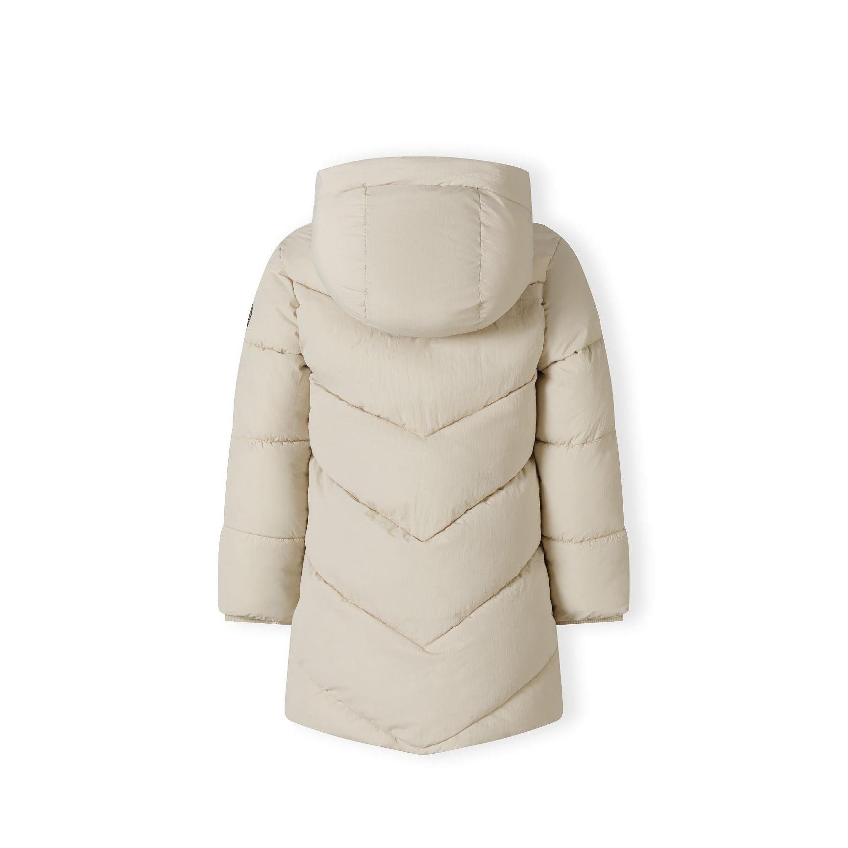 Close-up detail of circular embroidered patch with heart design and text on beige quilted puffer jacket fabric