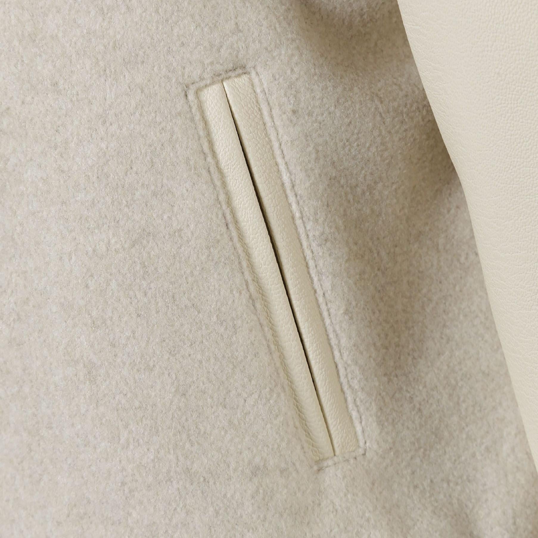 Close-up detail of side pocket on beige baseball jacket showing piped trim and quality construction