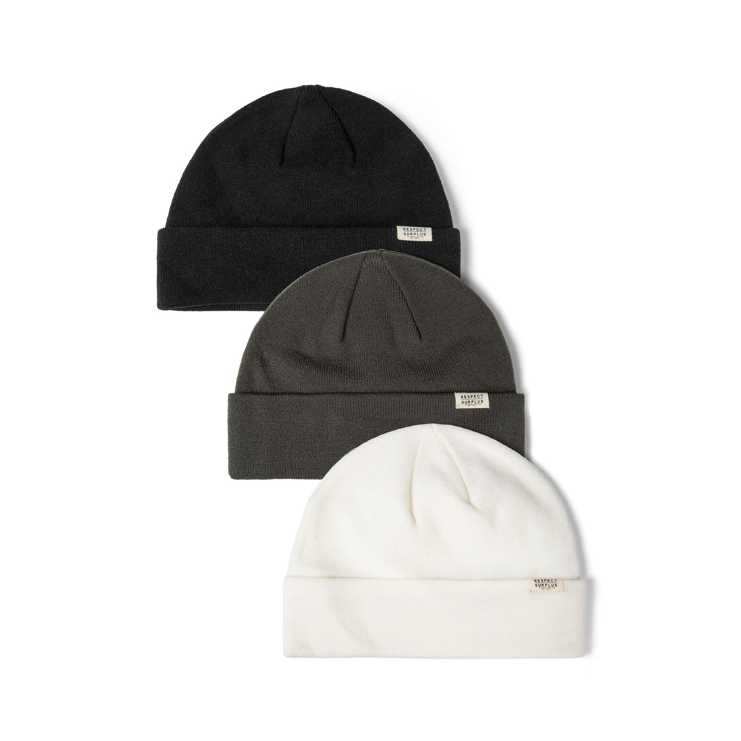 Three ribbed knit beanies arranged in stack - black on top, grey in middle, cream at bottom, each with small white brand label, white background