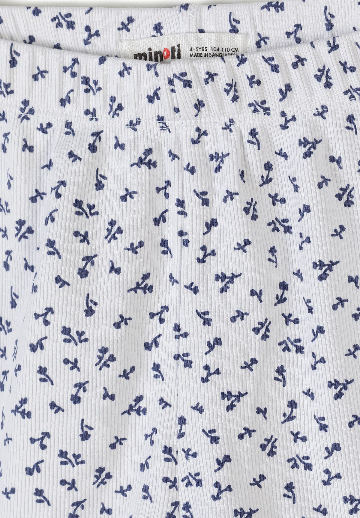 Close-up detail of white ribbed fabric with navy floral print pattern showing Minoti brand label