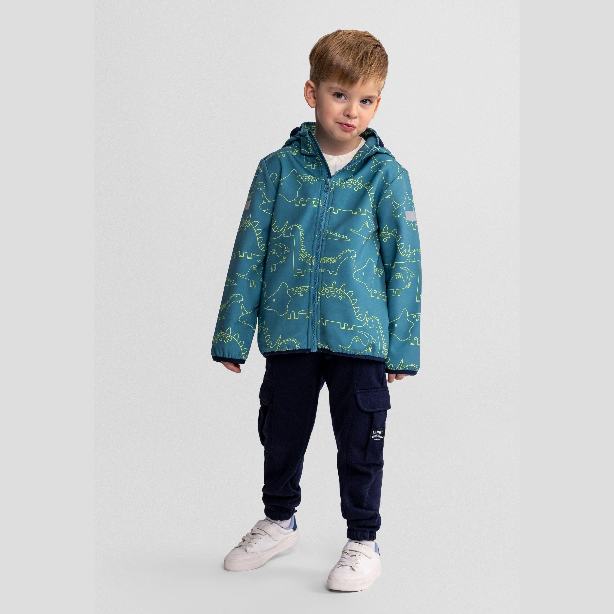 Boy wearing turquoise softshell jacket with dinosaur print and hood, paired with navy cargo trousers and white trainers on light grey background