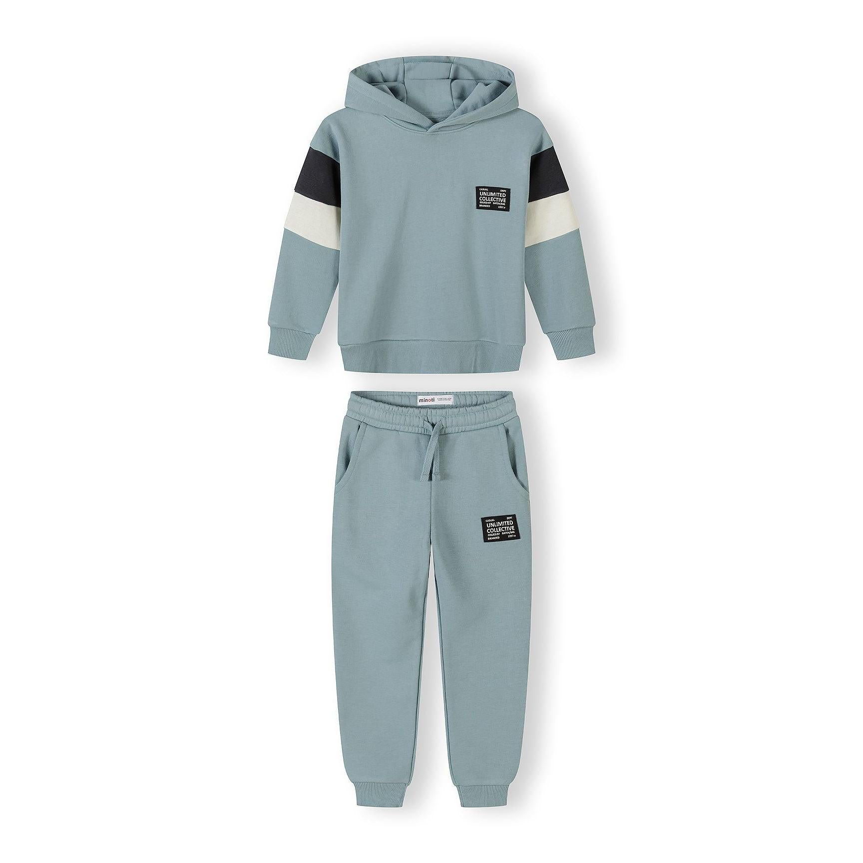 Complete sage blue tracksuit set with hooded sweatshirt and joggers featuring black and cream contrast panels on sleeves and branded patches, displayed flat on white background