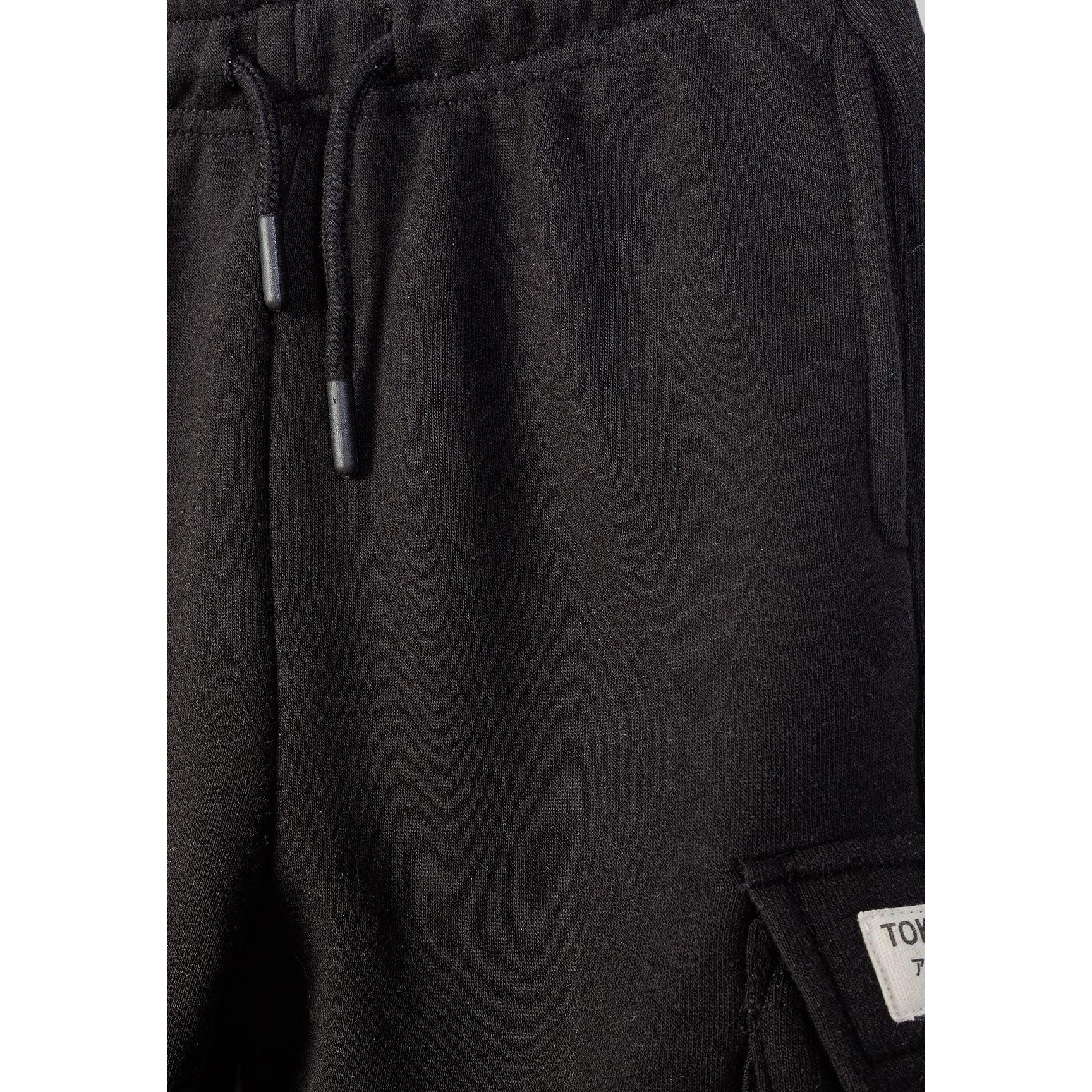 Detail shot of black cargo shorts waistband area showing drawstring ties and fabric texture with small label visible