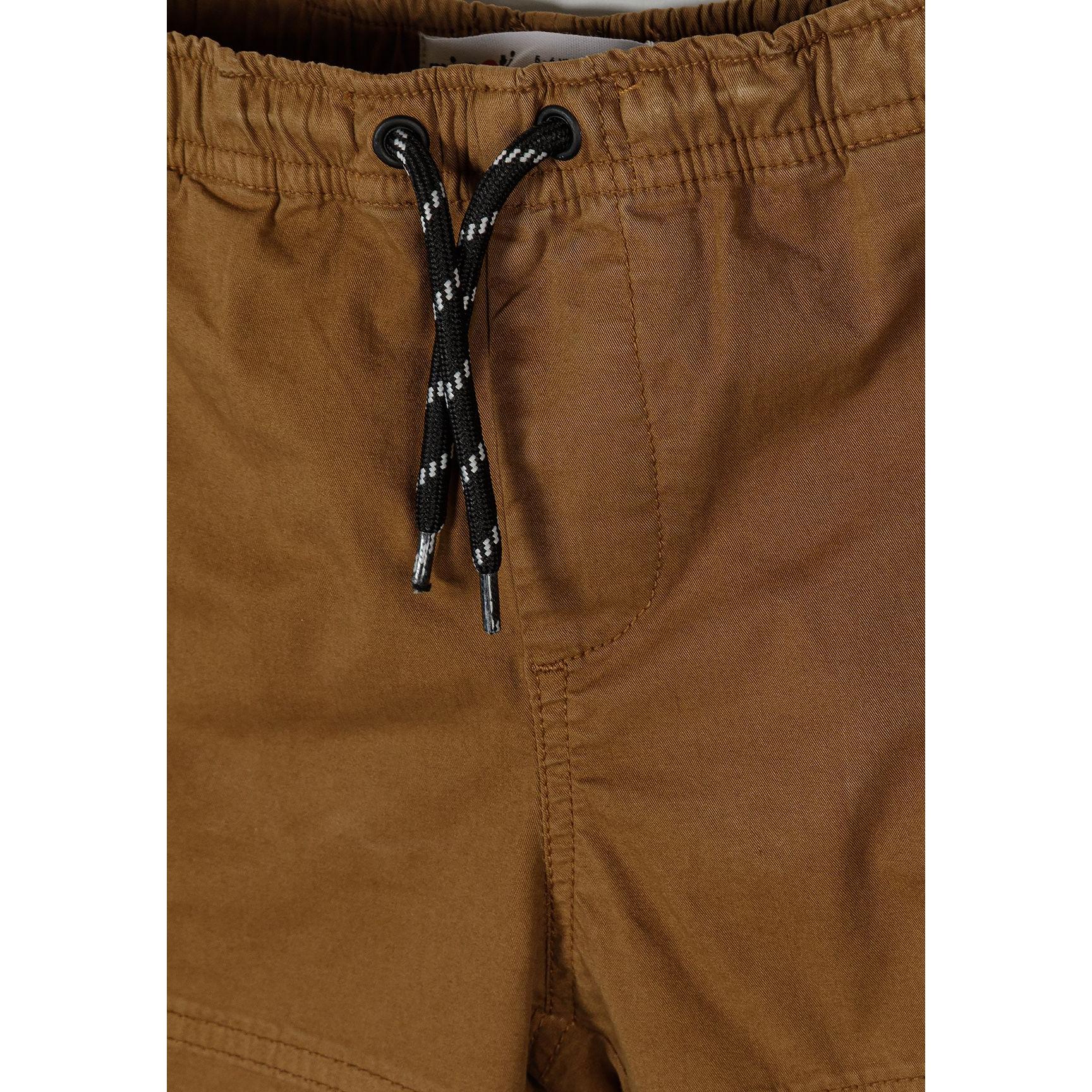 Close-up detail of camel brown combat shorts showing drawstring waist with black and white striped cord and elastic waistband construction