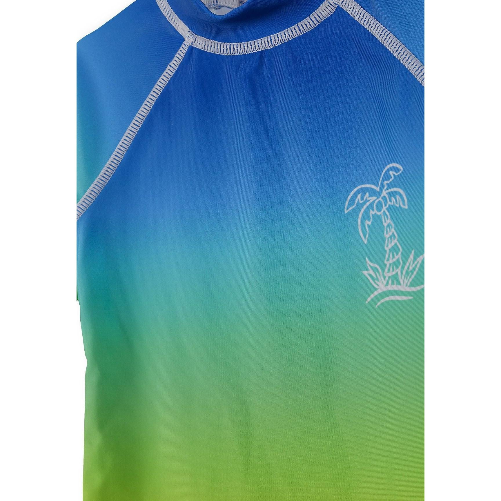 Close-up detail of royal blue to green ombré gradient on rash suit chest area showing palm tree print and crew neckline with contrast stitching