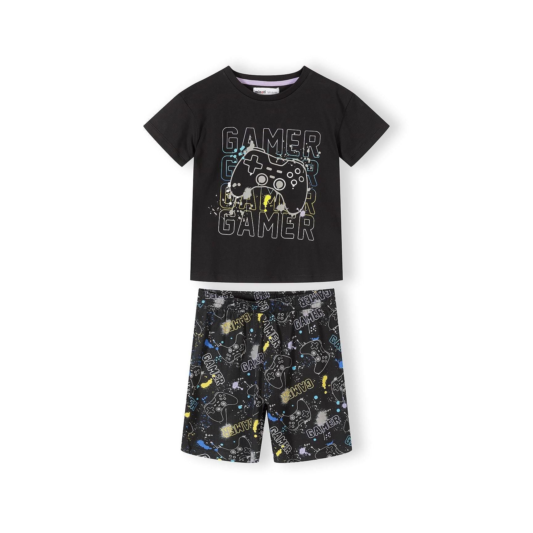 Close-up view of gaming pajama set showing black printed t-shirt with gamer graphics and grey shorts with colorful splatter pattern on white background