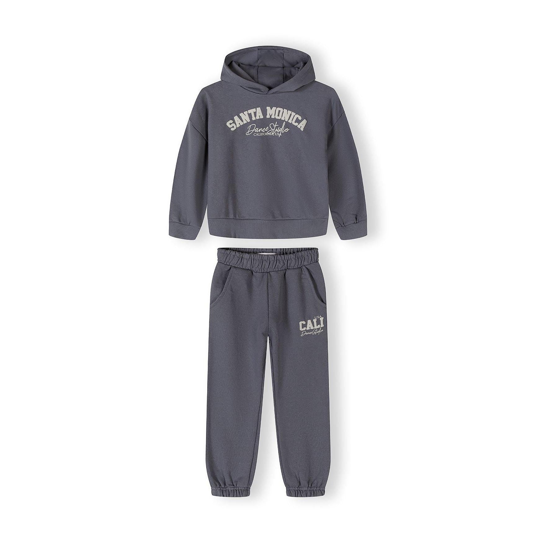 Close-up of blue-grey tracksuit bottoms showing elastic waistband and CALI USA Dance Studio text print on the leg