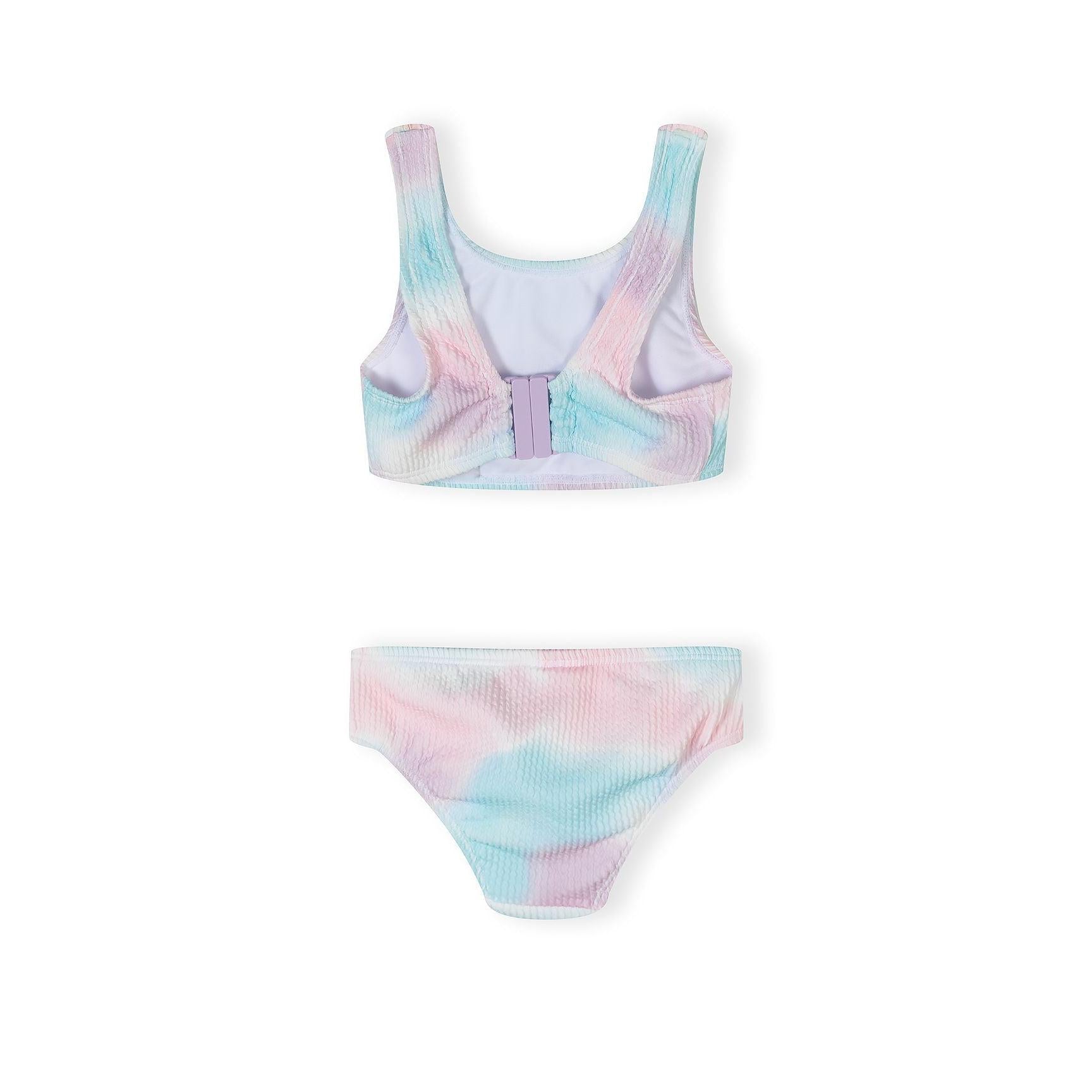 Close-up of ribbed texture bikini bottom in pink and blue tie-dye pattern on white background, showing Minoti brand label at waistband