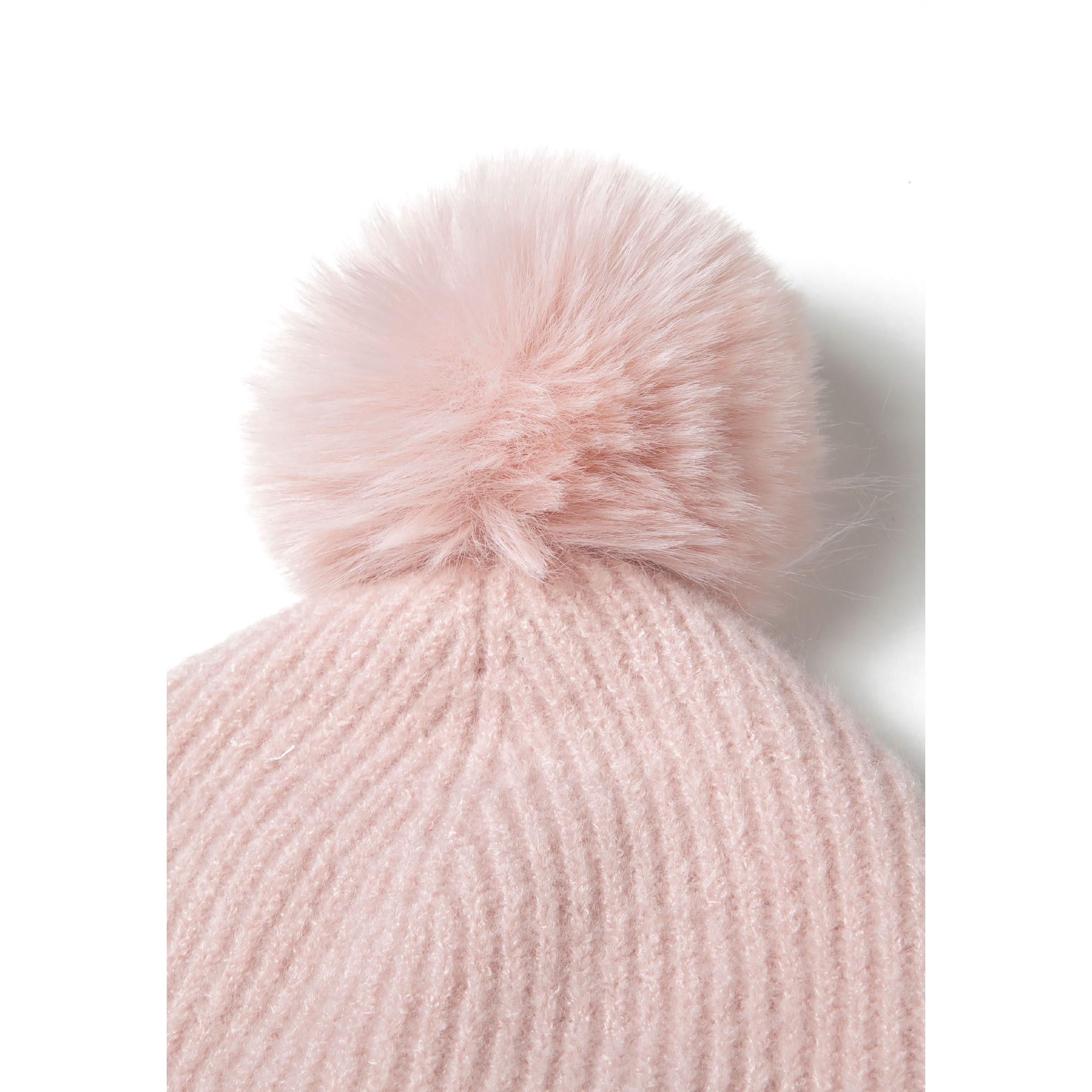 Close-up detail of pale pink ribbed knit fabric texture showing round metal Minoti brand badge