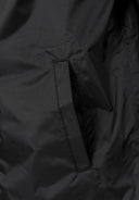 Close-up of waterproof fabric with a sleek pocket design on a black kids’ jacket sleeve.