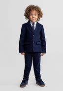 Young boy wearing a tailored navy blue blazer with notch lapel paired with matching trousers and a tie, showcasing kids fashion design.