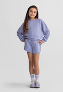 Young girl wearing a stylish blue sweatshirt and shorts set with ribbed cuffs and elasticated waist in a casual pose