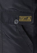 Detail of a black padded parka jacket featuring a button and logo badge.