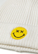 Detail of cream boys beanie with ribbed texture and yellow smiley badge.