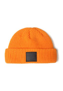 Close-up of a bright orange knitted fisherman hat with a badge detail.