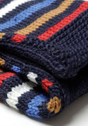 Detail of a knitted scarf with a striped pattern in navy, red, blue, and white.