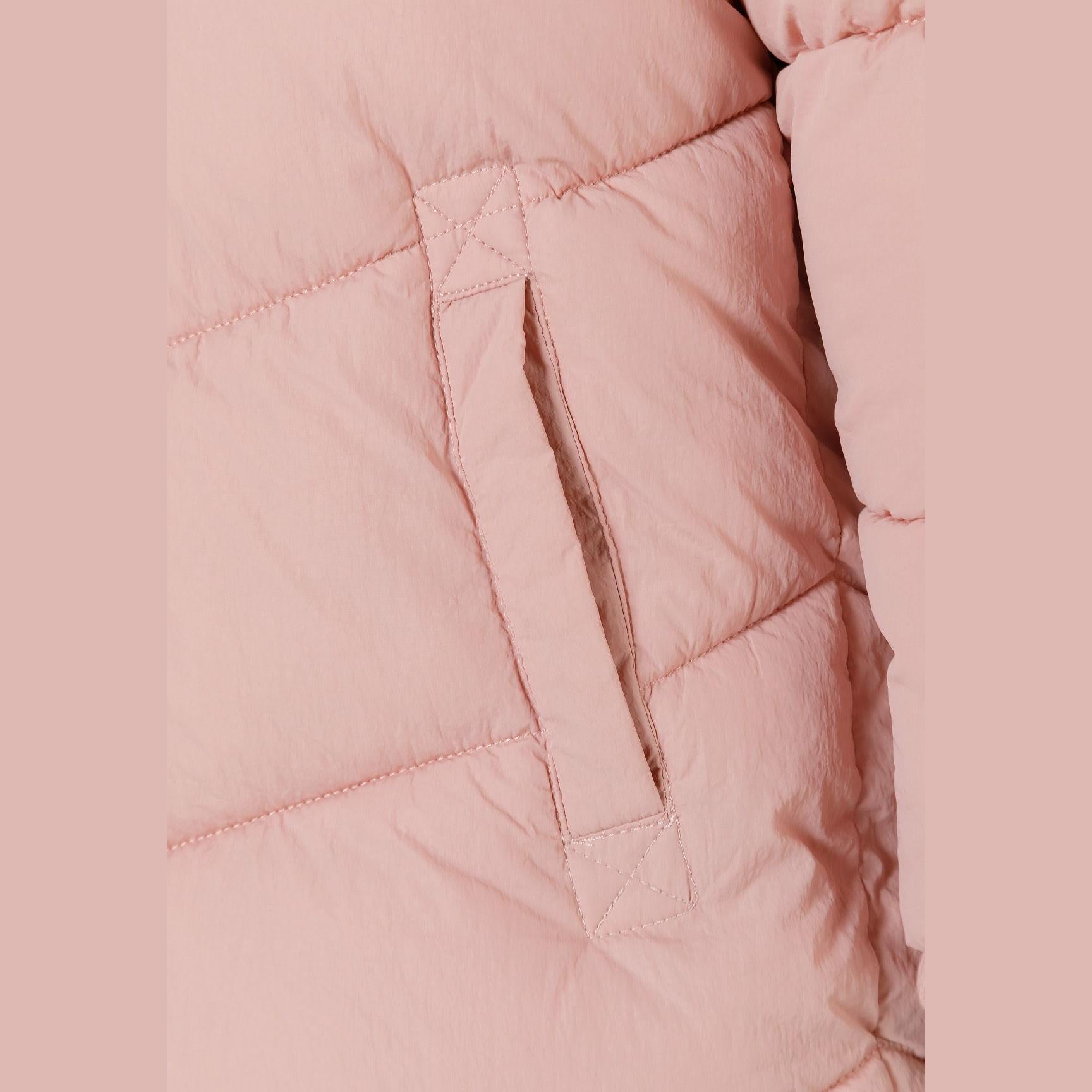 Close-up detail of pink quilted jacket showing side pocket with zip closure and diagonal stitching pattern