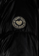 Detail of a shiny black padded jacket with a logo badge on the sleeve.