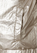 Detail of a girls reversible jacket with a metallic beige exterior and a side pocket.