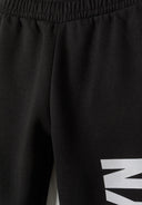 Detail of black girls tracksuit pants with elastic waistband and printed logo.