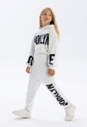 Girls hooded tracksuit in white, featuring printed accents, relaxed fit, and kangaroo pocket.