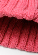 Detail of a pink knitted cable hat with a ribbed edge.