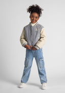 Girl smiling wearing a Girls baseball style jacket with faux leather sleeves grey 2-14y and casual jeans standing confidently