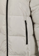 Detail of a cream long quilted winter jacket with a black zipper and padded filling.