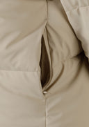 Detail of a beige quilted jacket with a zipper.