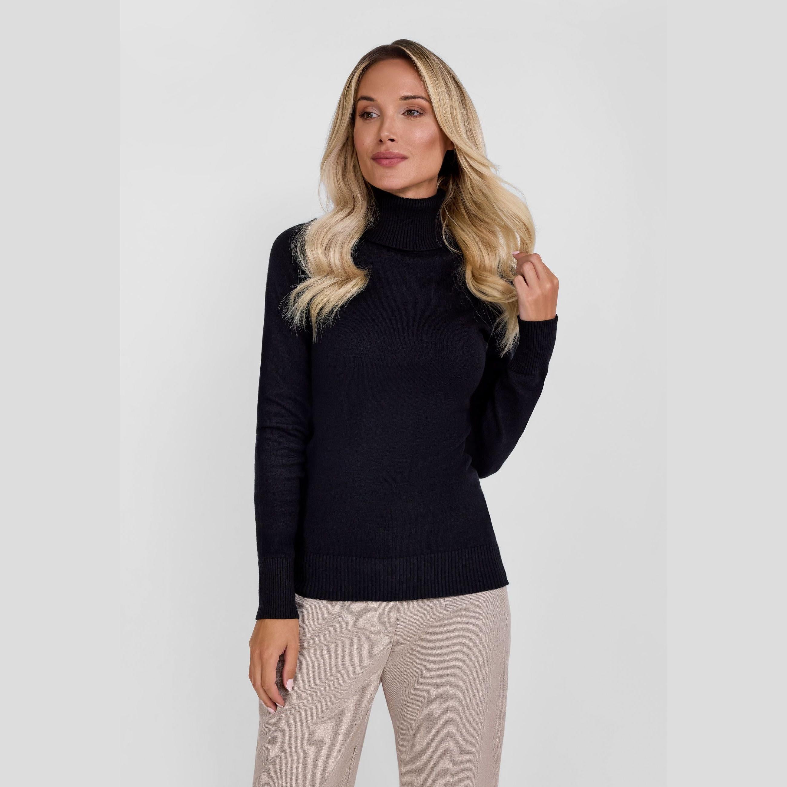 Woman wearing black turtleneck jumper with beige trousers against white background, showing front view and classic fit