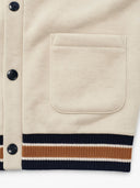 Detail of a cream buttoned sweatshirt with a large front pocket and ribbed hem.