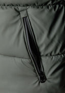 Detail of a khaki padded jacket showing a zipped pocket.