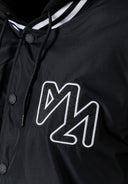 Close-up of a black men's baseball jacket featuring a logo and button details.