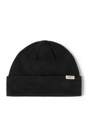 Close-up of a black ribbed beanie hat with a cuff and a subtle badge.