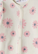 Detail of a girls' long sleeve sleepsuit with pink flower pattern and press stud fastenings.