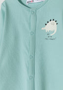 Detail of a mint green long-sleeved sleepsuit with dinosaur print and press stud fastening.