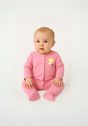 Girls long sleeve pyjama set in pink with feet, front view, featuring a decorative print.