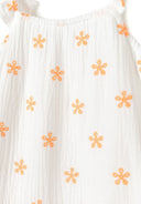 Detail of girls' white dress with orange embroidered flowers and frilled shoulder straps.