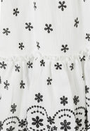 Detail of a cream girls dress with black floral embroidery and frilled hem.