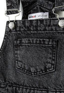 Detail of black denim girls' dungarees with adjustable braces and back pocket.