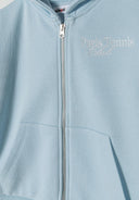 Close-up of a girls' oversized blue zip-through hoodie with a front pocket and embroidered detail.