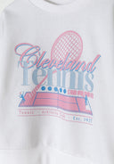 Detail of a girls' cream fleece crew neck sweatshirt featuring a colorful tennis graphic.