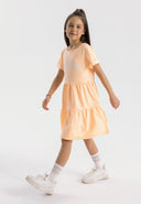 Girls short sleeve orange dress with tiered hem, featuring a round neckline and decorative print.