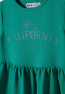 Close-up of a girls short sleeve green fleece dress featuring a tiered hem and palm tree print.