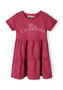 Girls pink tiered dress with short sleeves and round neckline, featuring a decorative print.