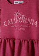 Close-up of a pink girls' dress with a tiered hem and palm tree print.