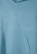 Detail of light blue girls' dress with hood, featuring NYC graphic and kangaroo pocket.