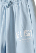 Detail of light blue jogger with side pocket and printed text.