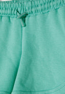 Detail of green shorts with elasticated waistband and adjustable drawstring.