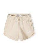 Detail of lightweight beige shorts with pockets and adjustable drawstring.